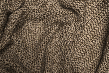 Crumpled folded brown knitted fabric background, woolen knitwear close up