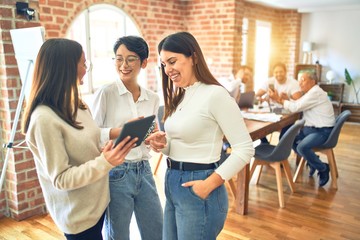 Business workers smiling happy. Standing with smile on face working together using tablet at the office