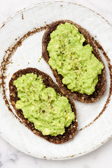 Mashed avocado cream on rye bread toast top view. Healthy vegan vegetarian appetizer snack breakfast food