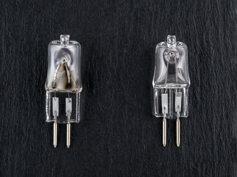 Two small halogen bulbs on a black background: one new and one burned out. gx6.35 bipin bulb for pilot light of photo studio monoblock flash light.