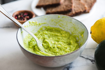 Mashed avocado sauce in bowl. Guacamole sauce, healthy vegan and vegetarian snack sauce
