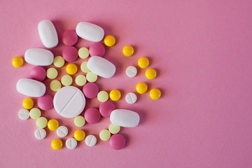 Obraz na płótnie Canvas Assorted pharmaceutical medicine! Pills of different colors and shapes on a pink background. Top view. The concept of the treatment of diseases! Coronavirus and antibiotics!