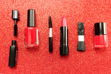 Makeup brush and decorative cosmetics on a red background.