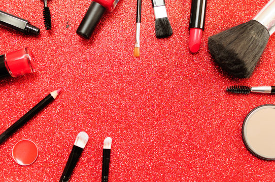 Makeup brush and decorative cosmetics on a red background.