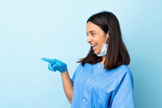 Surgeon woman over isolated blue background pointing finger to the side and presenting a product
