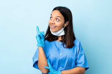 Surgeon woman over isolated blue background pointing up a great idea