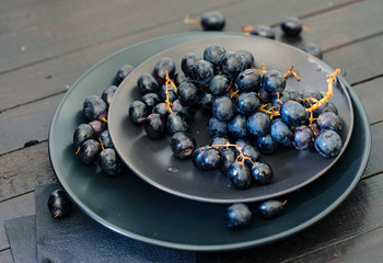 closeup view of black grapes in black plates at wooden table