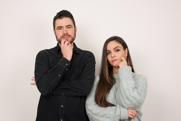 Isolated portrait of stylish European woman with hand near face and looking to the camera with doubtful and skeptical expression suspect and doubt. Isolated over gray background.
