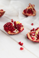 Pieces of ripe pomegranate fruit lie on a table on a white wooden background. Juicy fresh pomegranates. Organic Fruits