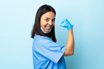 Surgeon woman over isolated blue background doing strong gesture