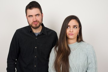 Gloomy, wondering young woman looking up with lips together, being upset thinking about something important, keeps hands down.
