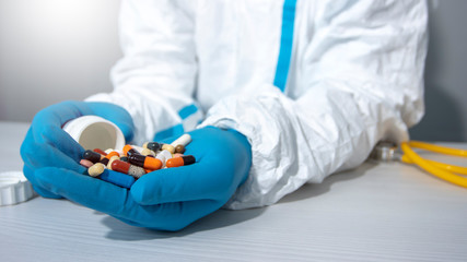 The doctor pours a handful of different pills into his cupped hands. Treatment concept