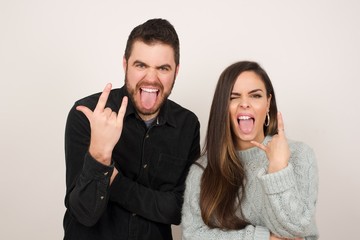 Portrait of a crazy girl showing tongue horns up gesture, expressing excitement of being on concert of band.