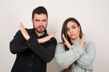 Young beautiful brunette girl wearing casual clothes standing over isolated background. Has rejection angry expression crossing hands doing refusal negative sign.