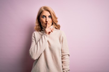 Middle age beautiful blonde woman wearing casual turtleneck sweater over pink background asking to be quiet with finger on lips. Silence and secret concept.