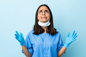 Surgeon woman over isolated blue background stressed overwhelmed