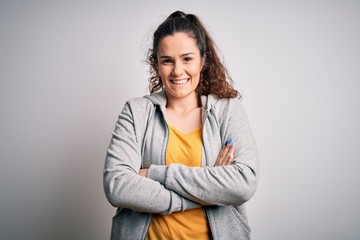 Obraz premium Young beautiful sportswoman with curly hair wearing sportswear over white background happy face smiling with crossed arms looking at the camera. Positive person.
