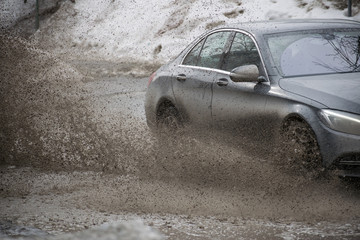 Car motion through big puddle of water splashes from the wheels on the street road. Water splash...