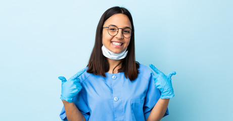 Surgeon woman over isolated blue background giving a thumbs up gesture