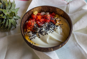 Fruit breakfast and natural yoghurt bowl. Watermelon, pineapple, pitahaya, black sesame seeds and greek yogurt. Healthy food concept on white background, top view flat lay