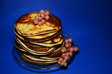 pancakes with berries on a transparent plate view from above blue background horizontal orientation