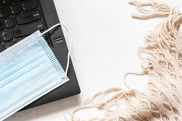 Work from home and quarantine concept. Laptop, surgical mask and cozy blanket on white background with copy space for your text. Epidemic prevention and distance education.