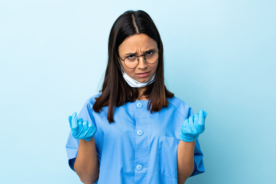 Surgeon woman over isolated blue background making money gesture but is ruined