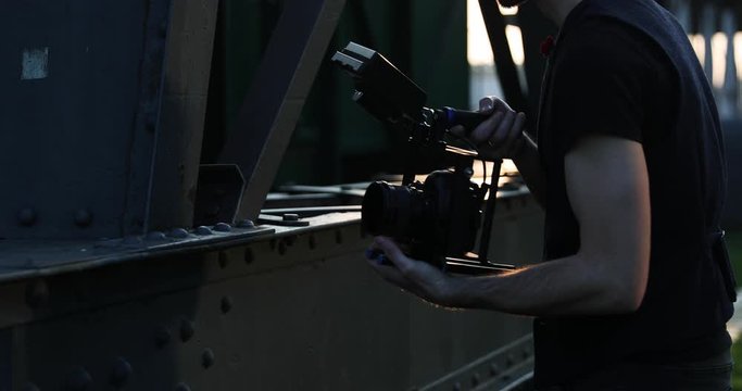 Filmmaker film with the camera handheld on sunset in a big city. Industrial
