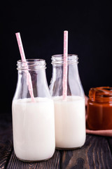 Two bottles of fresh milk with tubes and fresh homemade salted caramel n dark background.
