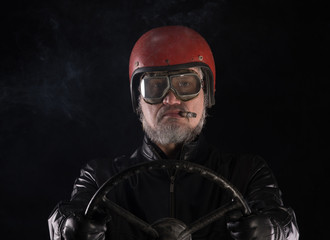 studio portrait of an old racing driver with a cigar on a black background