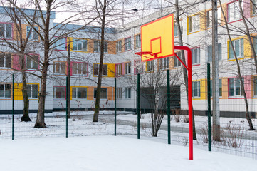 Snow-covered basketball court in the school yard.