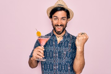 Young handsome hispanic bohemian hipster man with bear drinking a summer cocktail screaming proud...
