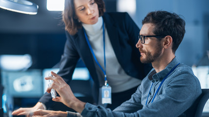 Futuristic Machine Engine Development Engineer Working on Computer at His Desk, Talks with Female...