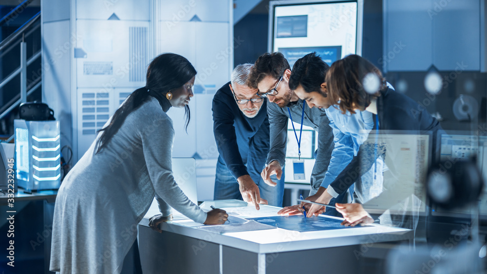 Leinwandbilder Engineers Meeting in Technology Research Laboratory: Engineers, Scientists and Developers Gathered Around Illuminated Conference Table Talking and Finding Solution, Inspecting Industrial Engine Design
