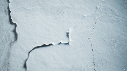 Aerial drone view of a river, covered with snow.