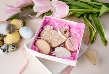 Beautiful Easter composition of eggs with natural colors, gingerbread, flowers, feathers.