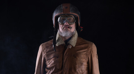 studio portrait of an old biker with a cigar on a black background
