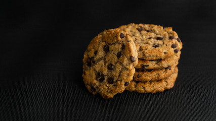 Stack of chocolate chips cookies, biscuits, shortbread on a black background. Close up. Copy space. Tasty crunchy dessert, breakfast, snack. Bakery, coffee house, homemade, recipe