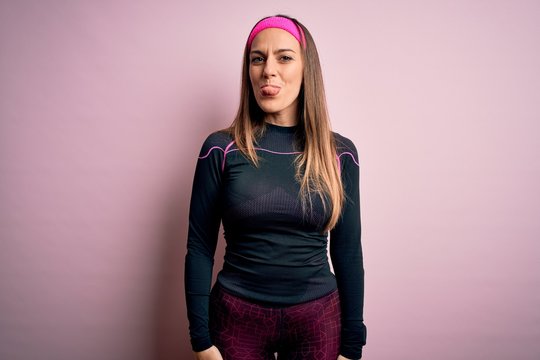 Young blonde fitness woman wearing sport workout clothes over isolated background sticking tongue out happy with funny expression. Emotion concept.