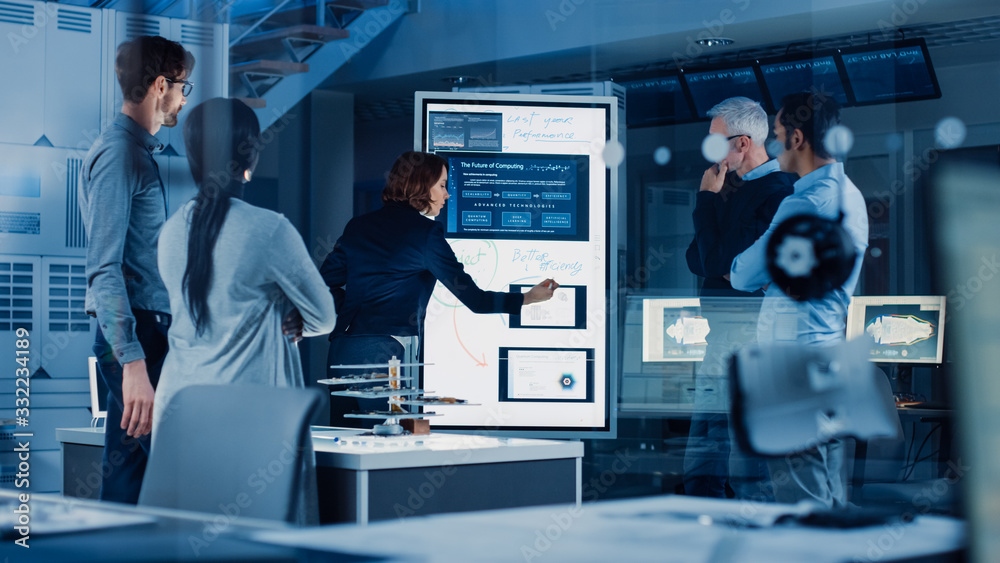 Poster Engineers Meeting in Research Laboratory: Female Engineer Leads Presentation Writes on Interactive Digital Whiteboard, Shows Blueprint, Data Analytics and Neural Network while Colleagues Listening