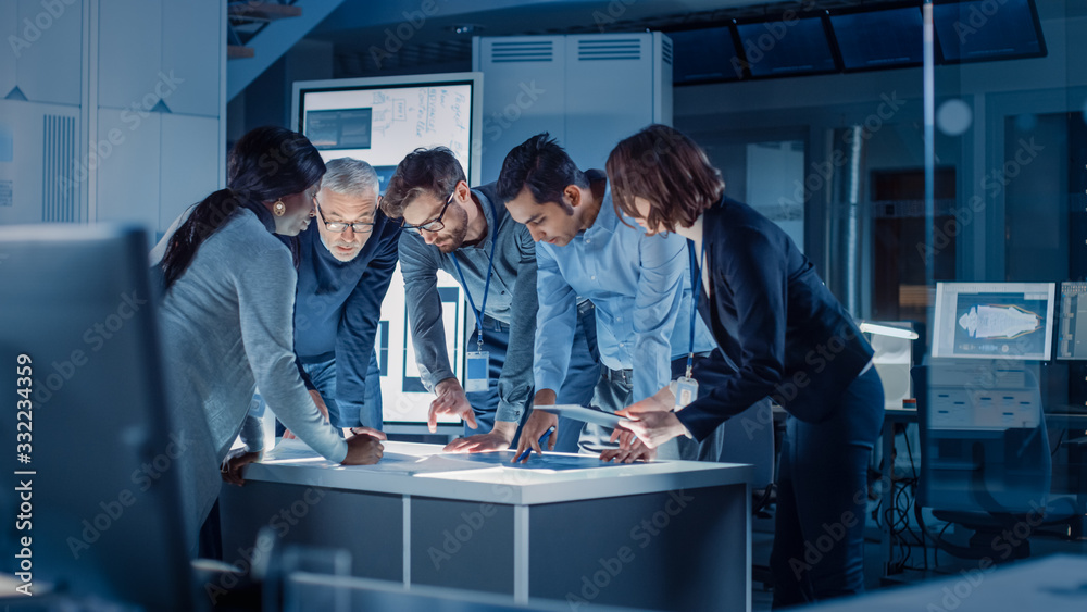 Poster Engineers Meeting in Technology Research Laboratory: Engineers, Scientists and Developers Gathered Around Illuminated Conference Table, Talking and Finding Solution. Industrial Design Facility