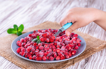 Frozen red wild strawberries in a spoon
