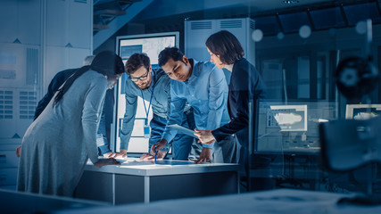 Fototapeta na wymiar Engineers Meeting in Technology Research Laboratory: Engineers, Scientists and Developers Gathered Around Illuminated Conference Table, Talking and Finding Solution. Industrial Design Facility