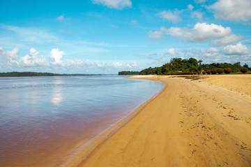 Panorama of a river beach with yellow sand stretching curved into the distance on a Sunny day against a turquoise sky. World tourism, landscape, tropics