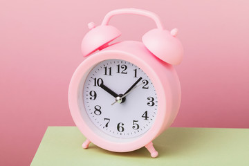 Alarm clock on a pink background, close-up