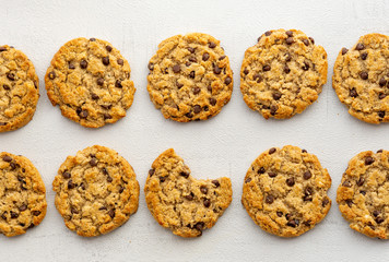 Chocolate chips crunchy cookies, biscuit on a table. One cookie bitten. Top view. Banner. Grey background. Snack, breakfast, fast food. Sweet tasty dessert. Isolated. Close up. Bakery concept