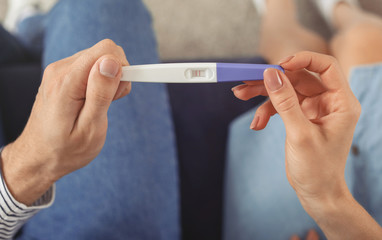 Young couple with pregnancy test at home, closeup