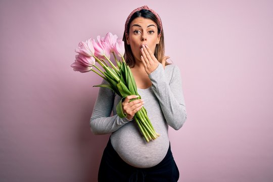 Young Beautiful Brunette Woman Pregnant Expecting Baby Holding Bouquet Of Tulips Cover Mouth With Hand Shocked With Shame For Mistake, Expression Of Fear, Scared In Silence, Secret Concept