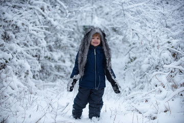 Fototapeta na wymiar Children run on snowy field. Childhood on countryside. Kids in winter clothes. Cute little kid enjoying in the winter park in snow.