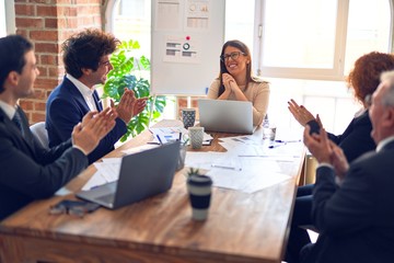 Group of business workers smiling happy and confident in a meeting. Working together looking at presentation using board and laptop applauding at the office.